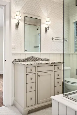 a bathroom with a granite countertop sink a mirror and a shower