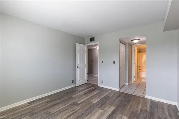 an empty room with wooden floor and window