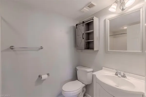 a bathroom with a toilet a sink a mirror and vanity