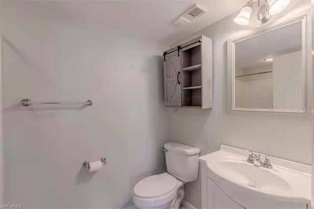 a bathroom with a toilet a sink a mirror and vanity