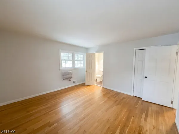 a view of an empty room with wooden floor and window