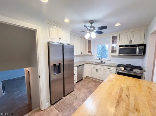 a kitchen with stainless steel appliances a refrigerator a sink a stove a microwave and cabinets