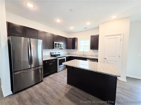 a large kitchen with stainless steel appliances granite countertop a refrigerator and a sink