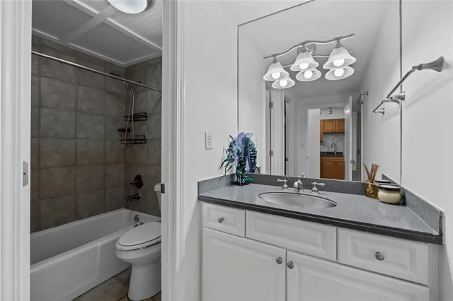 a bathroom with a granite countertop sink a toilet a mirror and shower