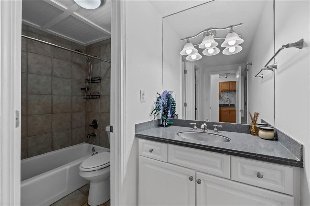 2479 Peachtree Street Northeast, Unit 912 Atlanta, GA 30305 - Photo 19 of 36 a bathroom with a granite countertop sink a toilet a mirror and shower