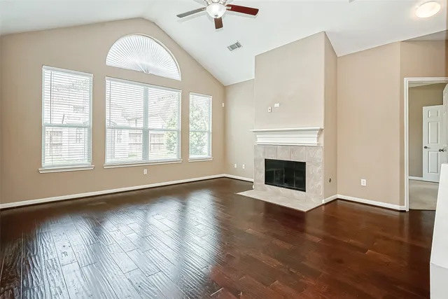 an empty room with wooden floor fan and windows