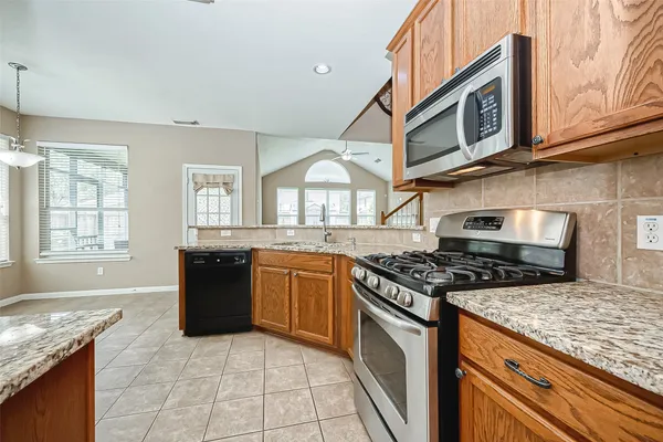 a kitchen with granite countertop a stove top oven microwave and refrigerator