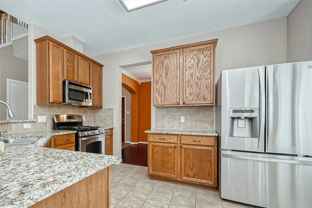a kitchen with granite countertop a refrigerator stove top oven and sink