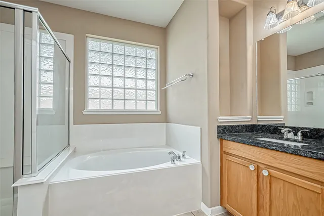 a bathroom with a granite countertop tub sink and mirror