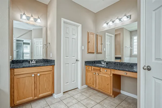 a spacious bathroom with a granite countertop sink a mirror and a shower