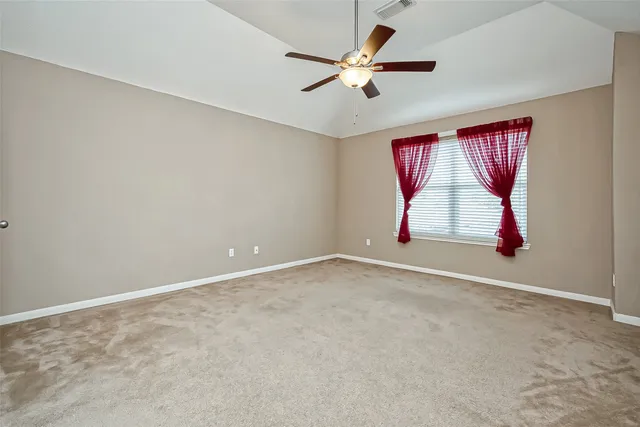 an empty room with ceiling fan and window