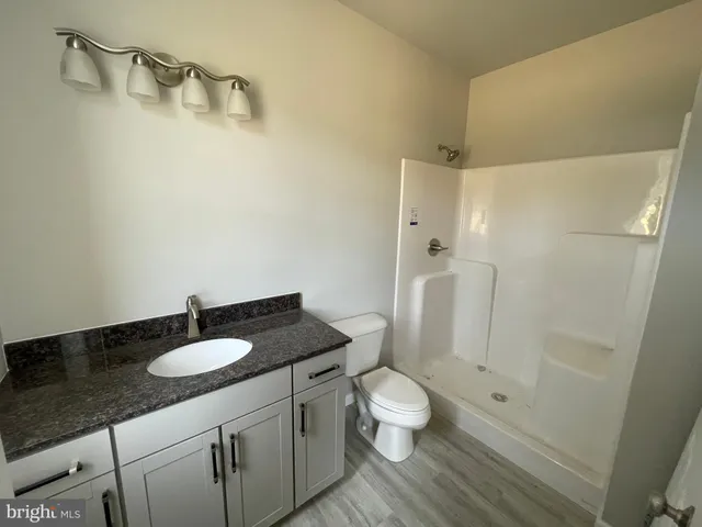a bathroom with a granite countertop sink toilet and shower