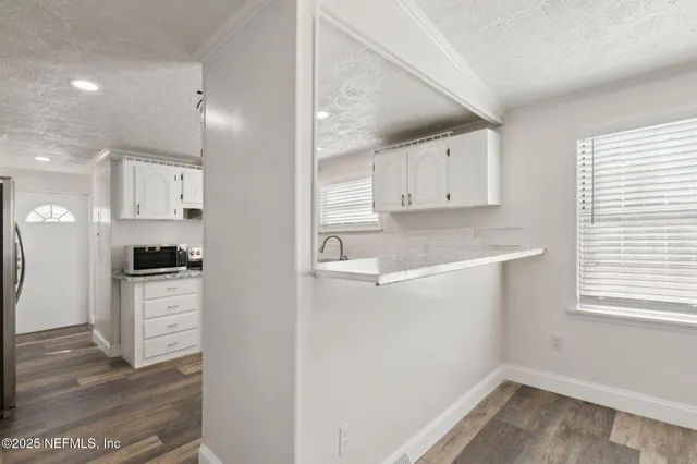 a kitchen with a refrigerator a stove top oven and white cabinets
