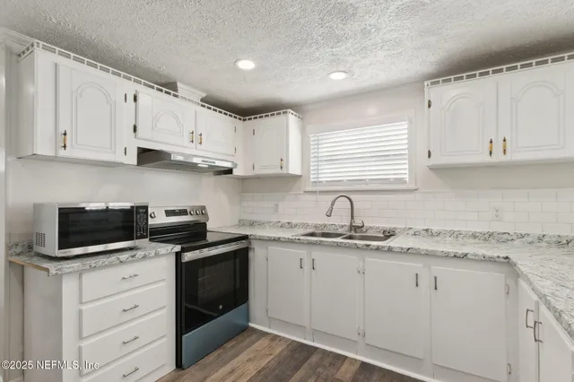 a kitchen with cabinets appliances a sink and a window