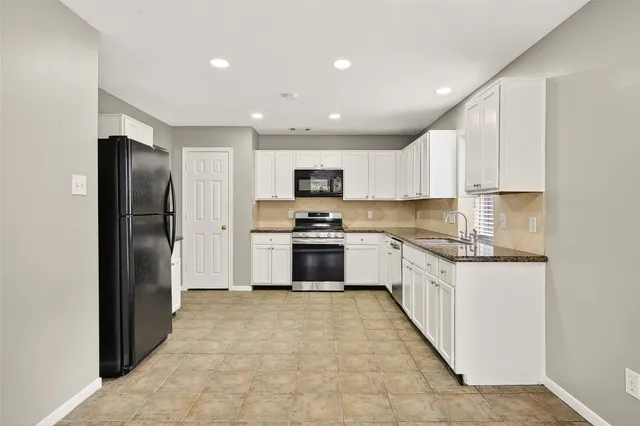 a kitchen with granite countertop a refrigerator and a sink