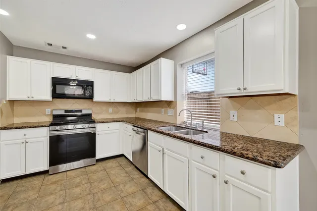 a kitchen with granite countertop a stove sink and cabinets