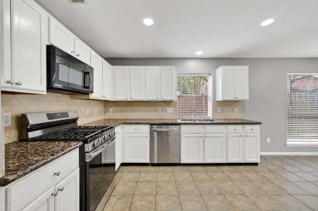 a kitchen with stainless steel appliances granite countertop a stove a sink and a microwave