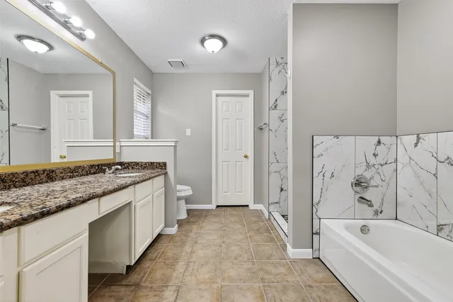 a spacious bathroom with a granite countertop tub sink and mirror