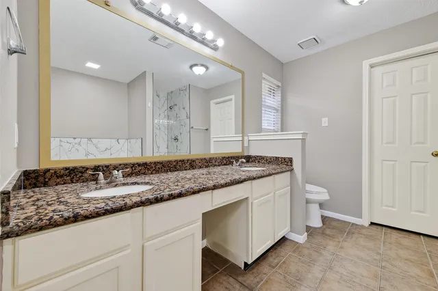 a bathroom with a granite countertop double vanity sink and a mirror