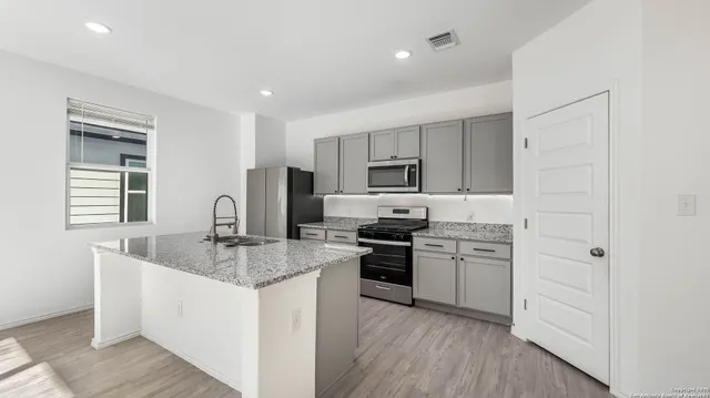 a kitchen with stainless steel appliances granite countertop a sink stove and refrigerator