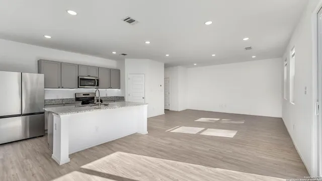 a kitchen with stainless steel appliances granite countertop a refrigerator and a stove top oven