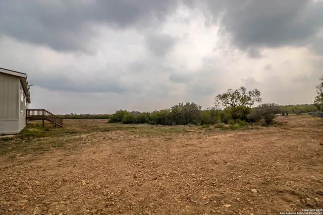 an empty room with wooden floor ceiling fan and windows