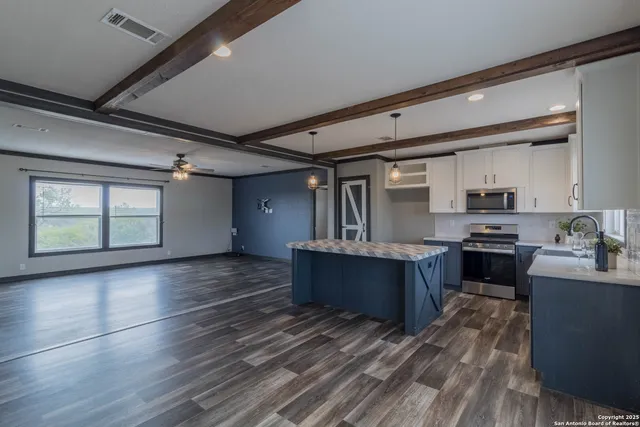 a kitchen with a stove center island wooden cabinets and a window