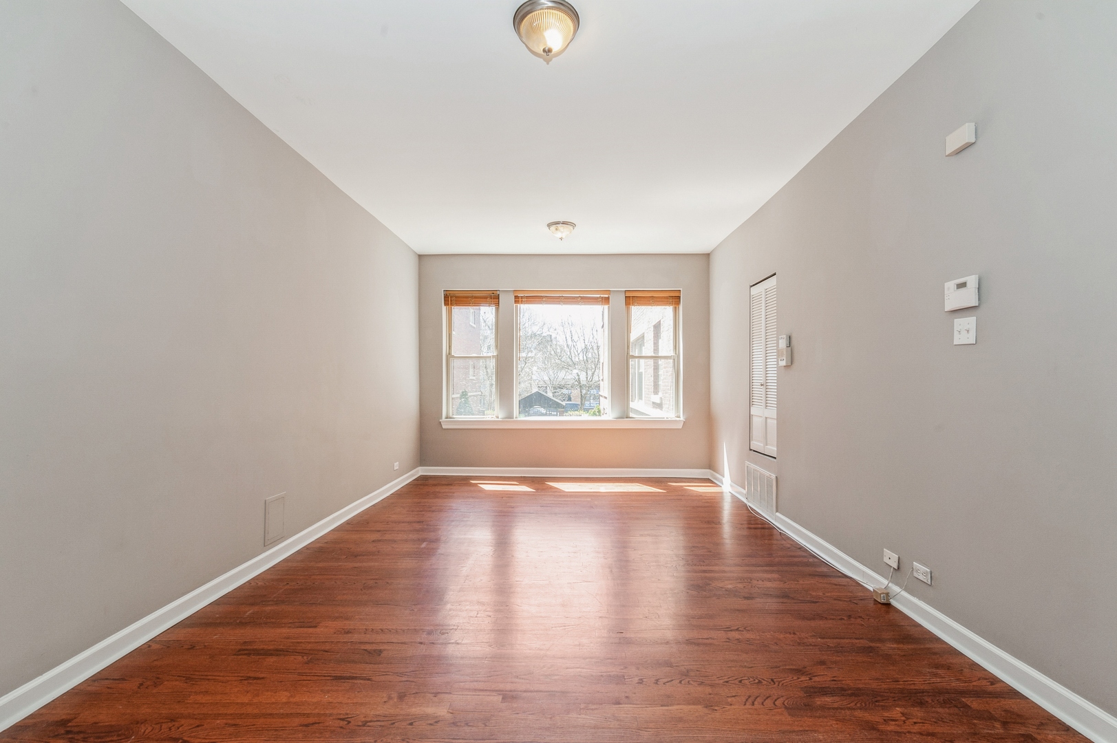 5743 North Ridge Avenue, Unit 1 Chicago, IL 60660 - Photo 2 of 12 a view of an empty room with wooden floor and a window