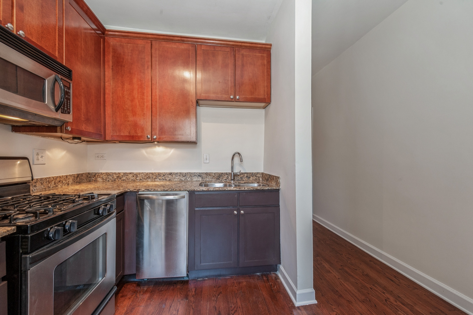 5743 North Ridge Avenue, Unit 1 Chicago, IL 60660 - Photo 4 of 12 a kitchen with granite countertop wooden cabinets and a stove top oven