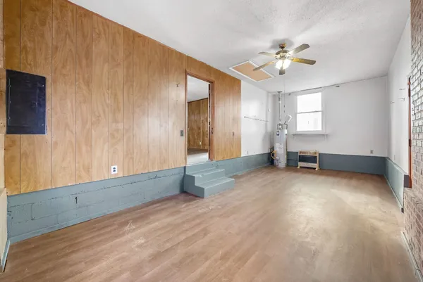 a view of an empty room with chandelier fan and windows