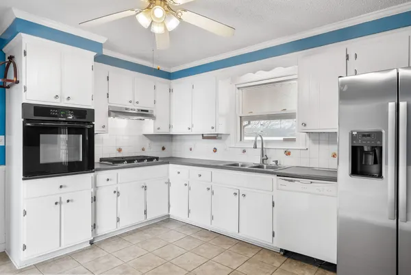 a kitchen with granite countertop white cabinets white stainless steel appliances and sink