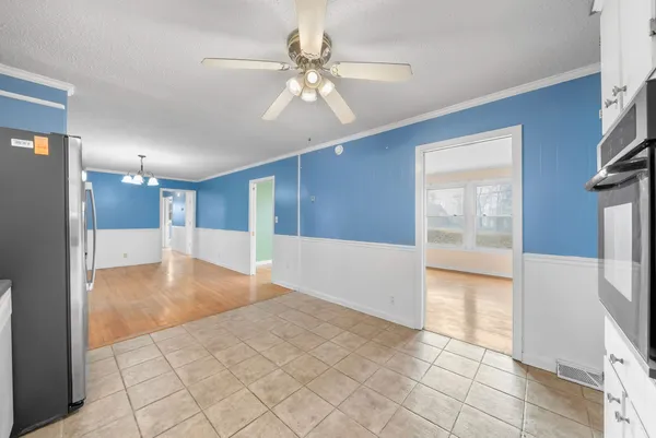 a view of an empty room with window and chandelier fan