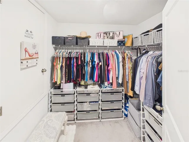 a view of walk in closet with clothes and shoes