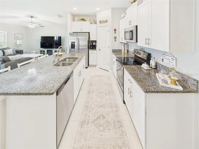 a large kitchen with granite countertop a sink and a stove top oven