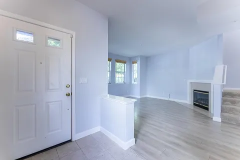 an empty room with wooden floor fireplace and windows