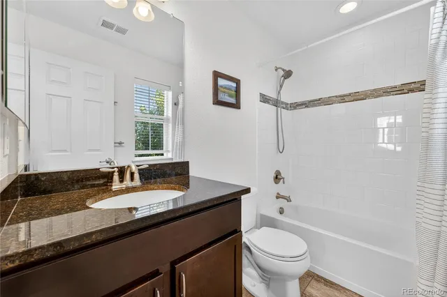 a bathroom with a granite countertop sink toilet a large mirror a shower and a bathtub