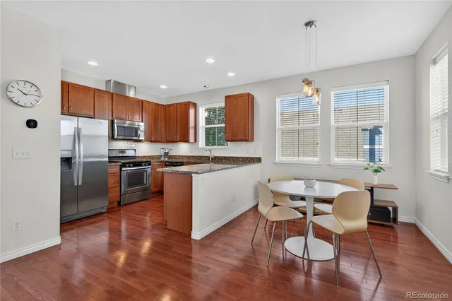 a kitchen with stainless steel appliances granite countertop a stove top oven a sink dishwasher a refrigerator and white cabinets with wooden floor