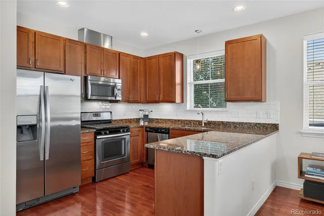 a kitchen with stainless steel appliances granite countertop a sink stove microwave and refrigerator