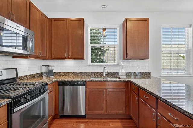 a kitchen with stainless steel appliances granite countertop a stove a sink and a microwave