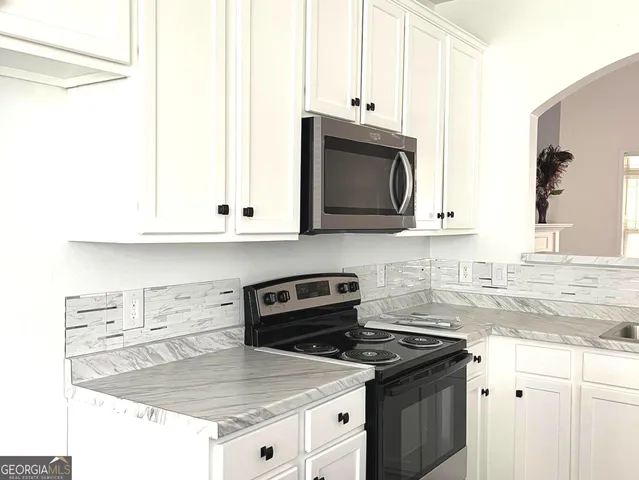 a kitchen with stainless steel appliances granite countertop a sink stove and microwave