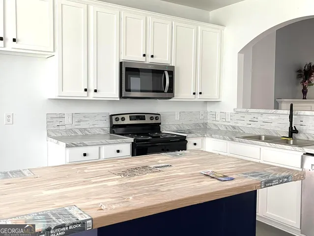 a kitchen with stainless steel appliances granite countertop a sink a stove and white cabinets