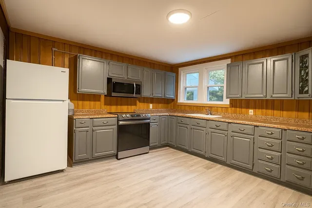 a kitchen with stainless steel appliances granite countertop a refrigerator sink and wooden cabinets