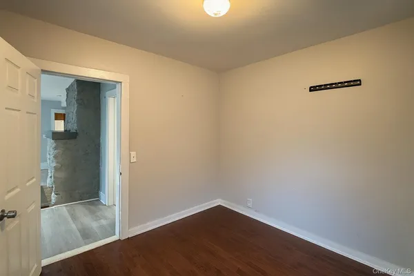 an empty room with wooden floor and mirror