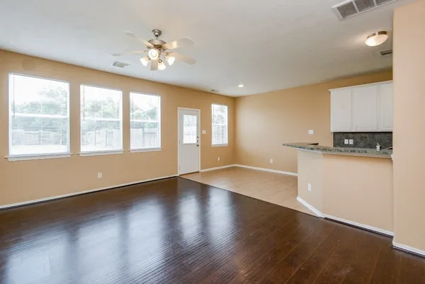 a view of an empty room with a window and wooden floor