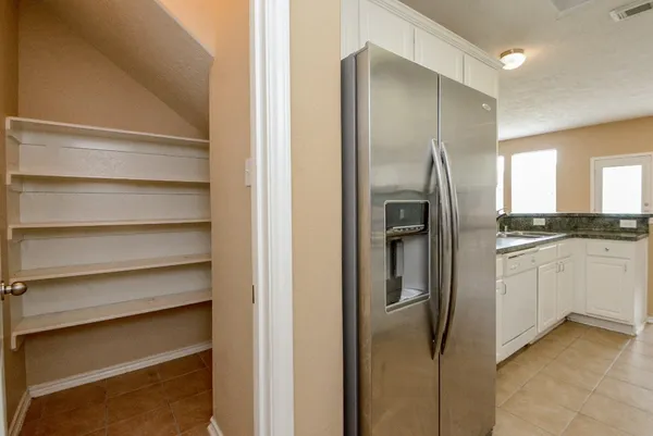 a kitchen with a refrigerator and white cabinets