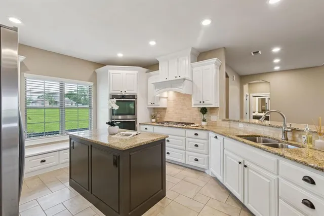 a kitchen with granite countertop stainless steel appliances sink stove and cabinets