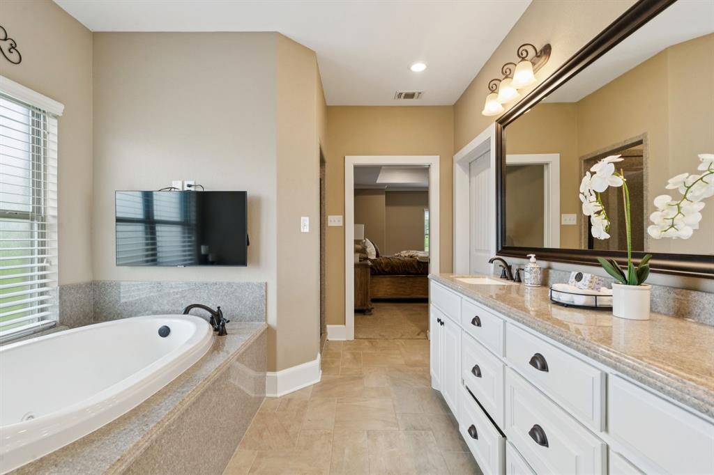 320 Tate Circle Sherman, TX 75090 - Photo 22 of 40 a bathroom with a tub a double vanity sink and a large mirror