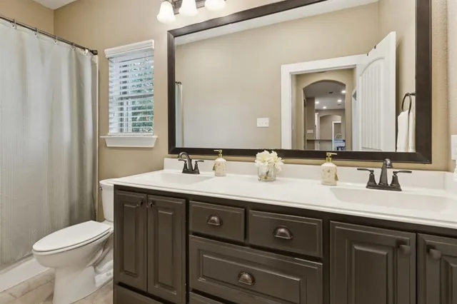 a bathroom with a granite countertop sink vanity mirror and toilet