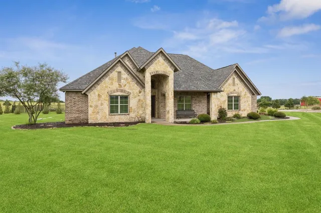 a view of a house with a big yard and large trees