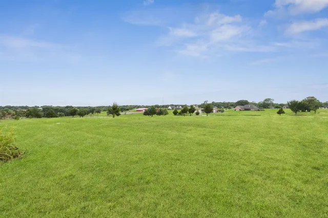 a view of a field with lawn chairs and large trees
